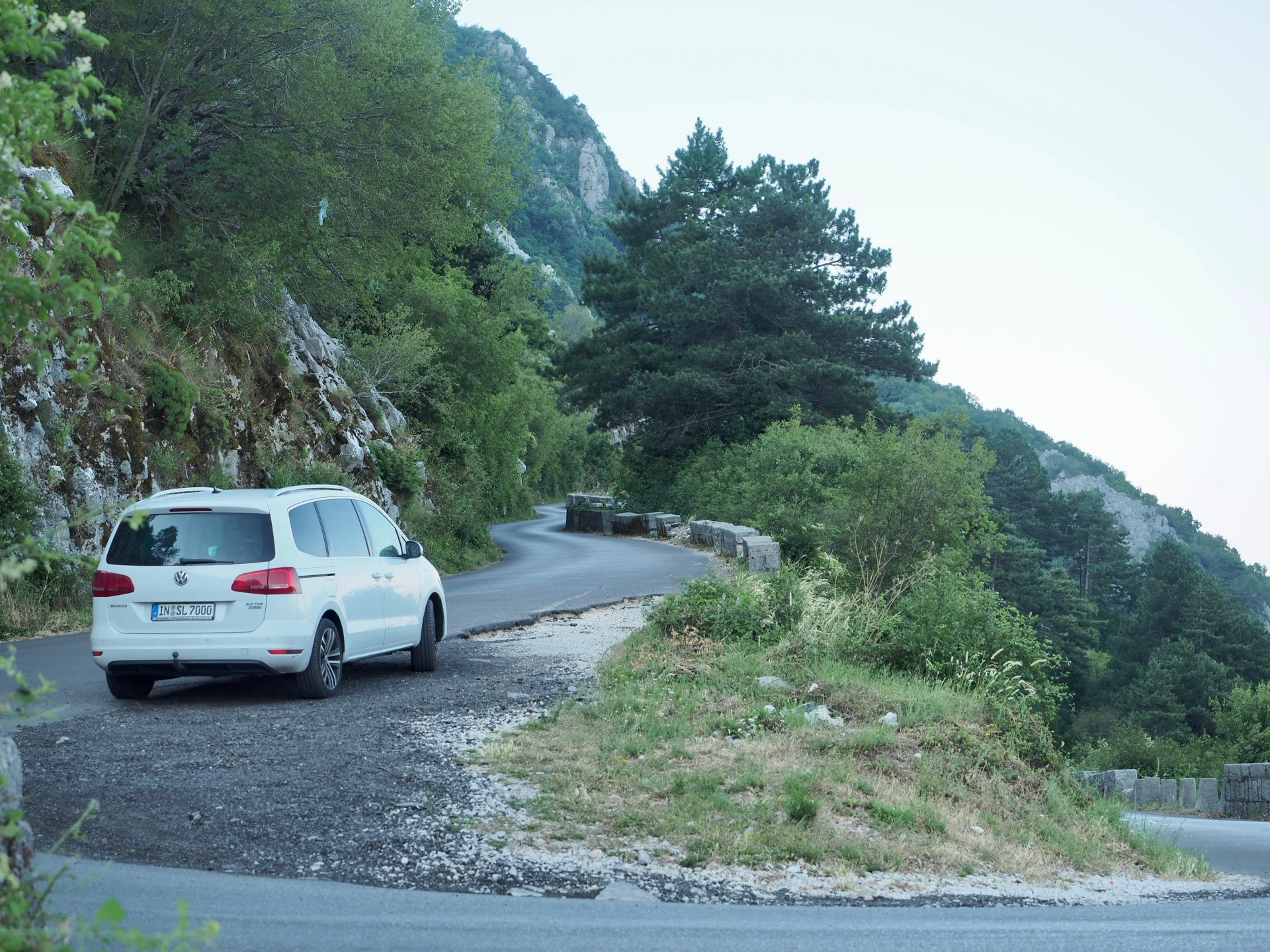 Weißer VW Sharan auf einer kurvigen Bergstraße.