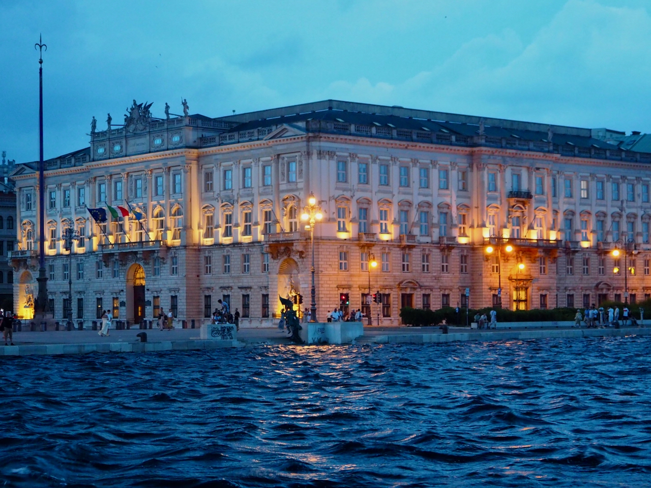 Die Innenstadt von Triest mit beleuchteten Gebäuden am Abend.